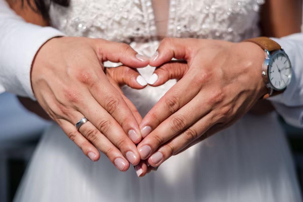 Detalle de los anillos en una boda Manos de los novios formando un corazón, con los anillos de matrimonio a la vista