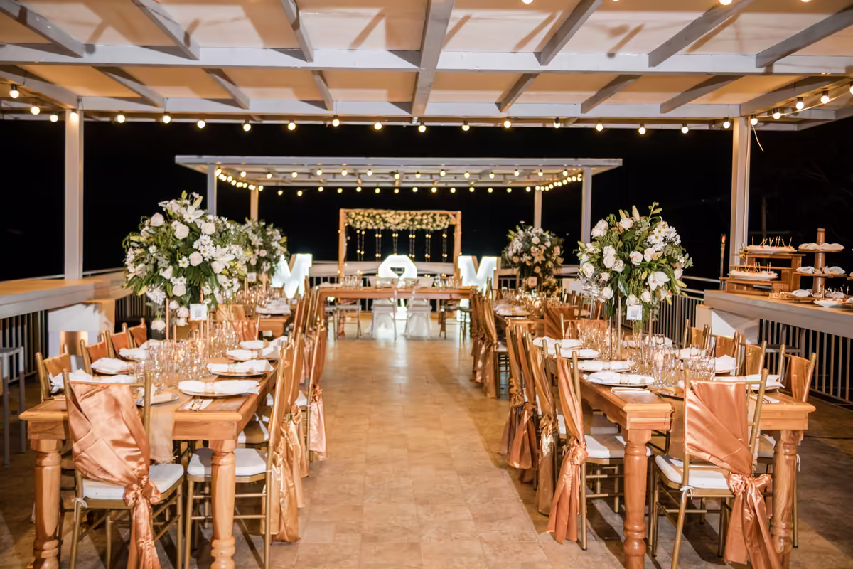 Eventos en Villeta, Cundinamarca Salón de recepción montado con mesas largas y luces colgantes durante una boda nocturna en Villeta