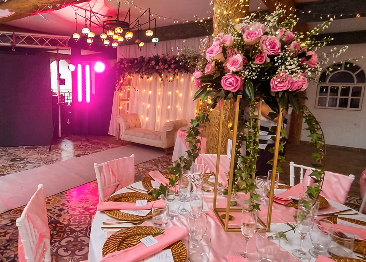 Fiesta de quince años decorada en Villeta Salón de quince años iluminado en rosa, con centro floral alto y mesa larga vestida de rosa, en Villeta